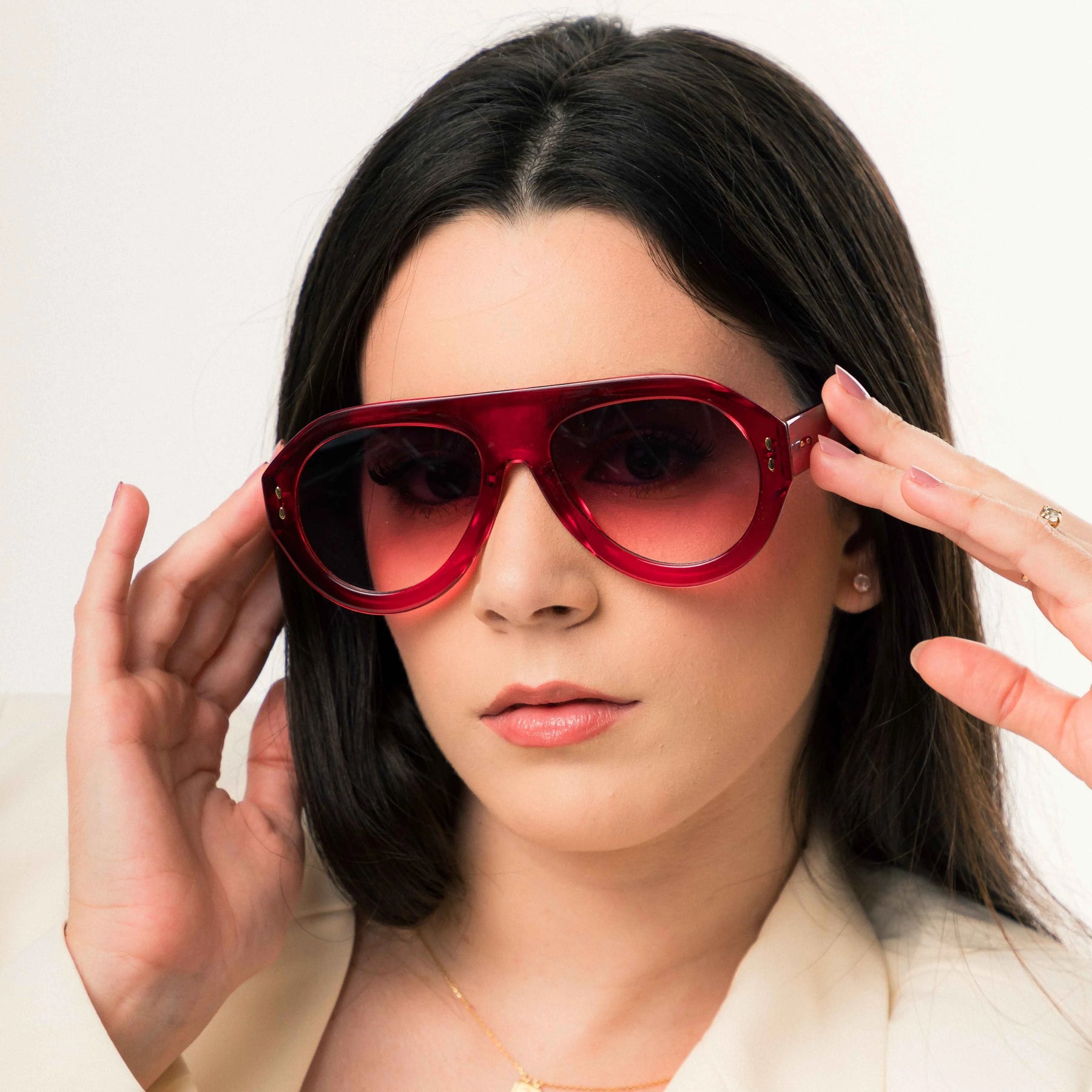Modelo utilizando óculos de sol feminino Rosa Coral Miranda, armação Vermelha e lente Lilás – estilo sofisticado e proteção UVA e UVB 400 para os olhos.