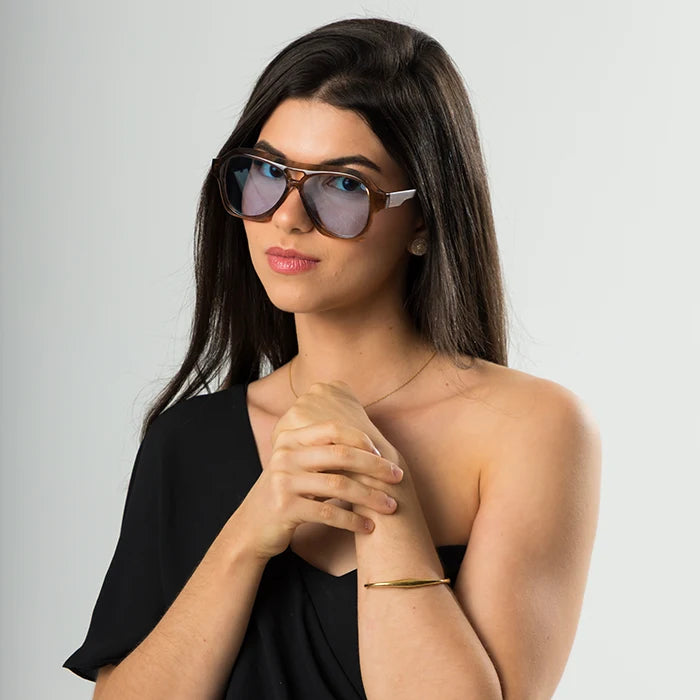 Modelo utilizando óculos de sol feminino Rosa Coral Noasca, armação Marrom e lente Azul – estilo sofisticado e proteção UVA e UVB 400 para os olhos.