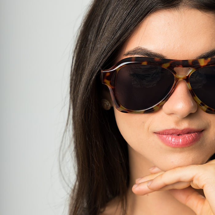 Modelo utilizando óculos de sol feminino Rosa Coral Noasca, armação Tartaurga e lente Marrom – estilo sofisticado e proteção UVA e UVB 400 para os olhos.