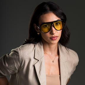 Modelo utilizando óculos de sol feminino Rosa Coral Veneto, armação Preta e lente Amarela – estilo sofisticado e proteção UVA e UVB 400 para os olhos.
