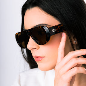 Modelo utilizando o Óculos de sol feminino máscara Rosa Coral Mantova, armação tartaruga e lente marrom  – estilo sofisticado e proteção UVA e UVB 400 para os olhos.