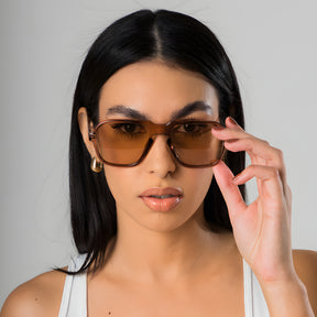 Modelo utilizando óculos de sol feminino Rosa Coral Messina, armação Marrom e lente Marrom – estilo sofisticado e proteção UVA e UVB 400 para os olhos.