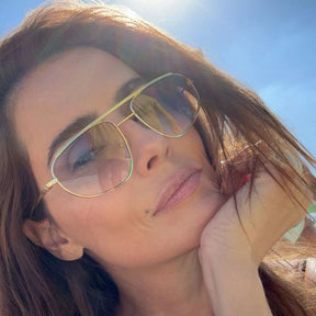 Modelo utilizando óculos de sol feminino Rosa Coral Aurelia, armação Dourado e lente Azul Gradiente – estilo sofisticado e proteção UVA e UVB 400 para os olhos.
