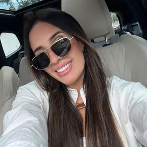 Modelo utilizando óculos de sol feminino Rosa Coral Aurelia, armação Dourado e lente Cinza – estilo sofisticado e proteção UVA e UVB 400 para os olhos.