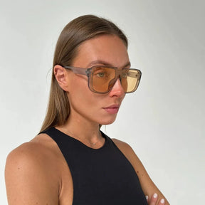 Modelo utilizando óculos de sol feminino Rosa Coral Castelli, armação Cinza e lente – Amarela estilo sofisticado e proteção UVA e UVB 400 para os olhos.