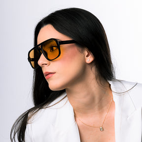 Modelo utilizando óculos de sol feminino aviador Rosa Coral Marino, armação Preta e lente Amarela  – estilo sofisticado e proteção UVA e UVB 400 para os olhos.