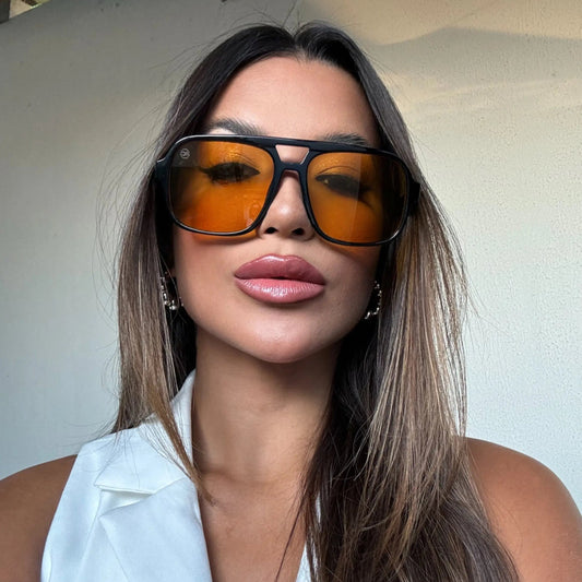 Modelo utilizando óculos de sol feminino aviador Rosa Coral Marino, armação Preta e lente Amarela – estilo sofisticado e proteção UVA e UVB 400 para os olhos.