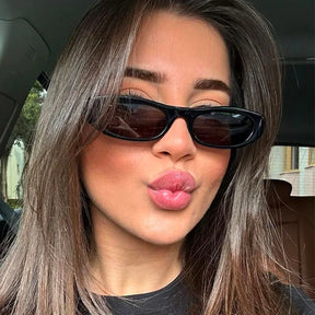 Modelo utilizando óculos de sol feminino Rosa Coral Matera, armação Preta e lente Marrom – estilo sofisticado e proteção UVA e UVB 400 para os olhos.