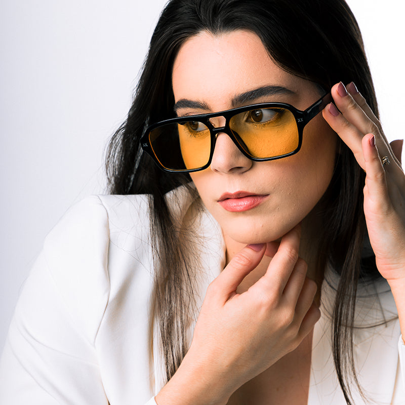 Modelo utilizando óculos de sol feminino Rosa Coral Mira, armação Preta e lente Amarela – estilo sofisticado e proteção UVA e UVB 400 para os olhos.