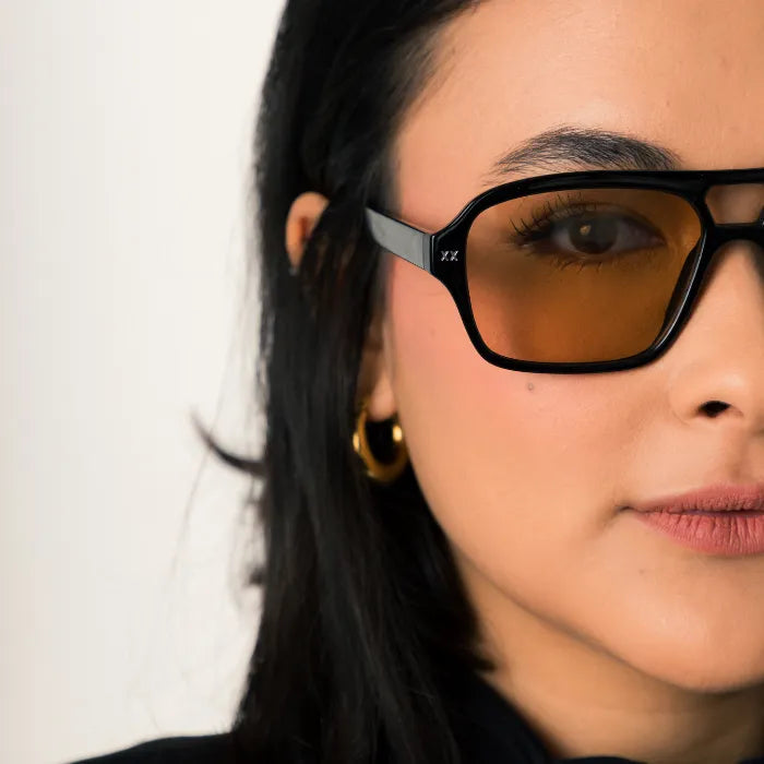 Modelo utilizando óculos de sol feminino Rosa Coral Mira, armação Preta e lente Marrom – estilo sofisticado e proteção UVA e UVB 400 para os olhos.