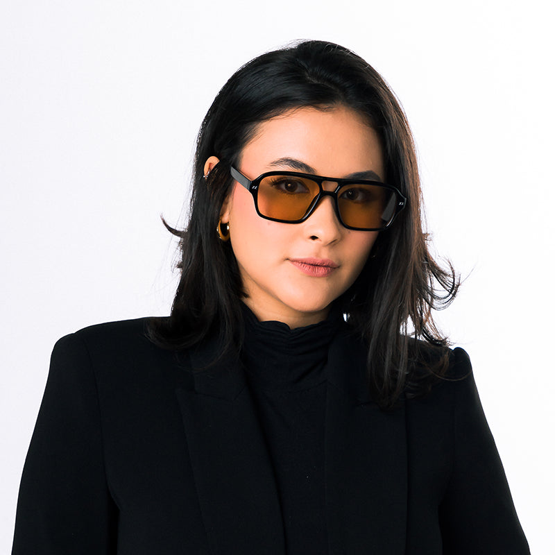Modelo utilizando óculos de sol feminino Rosa Coral Mira, armação Preta e lente Marrom – estilo sofisticado e proteção UVA e UVB 400 para os olhos.