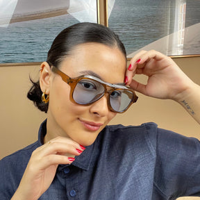 Modelo utilizando óculos de sol feminino Rosa Coral Noasca, armação Marrom e lente Azul – estilo sofisticado e proteção UVA e UVB 400 para os olhos.
