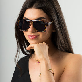 Modelo utilizando óculos de sol feminino Rosa Coral Noasca, armação Tartaurga e lente Marrom – estilo sofisticado e proteção UVA e UVB 400 para os olhos.
