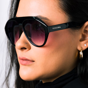 Modelo utilizando óculos de sol feminino Rosa Coral Norma, armação Preta e lente Gradiente – estilo sofisticado e proteção UVA e UVB 400 para os olhos.