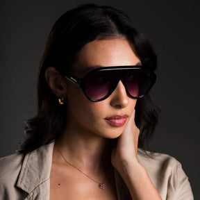 Modelo utilizando óculos de sol feminino Rosa Coral Norma, armação Preta e lente Gradiente – estilo sofisticado e proteção UVA e UVB 400 para os olhos.