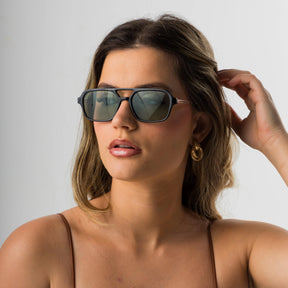 Modelo utilizando óculos de sol feminino Rosa Coral Piemonte, armação Preta e lente verde – estilo sofisticado e proteção UVA e UVB 400 para os olhos.