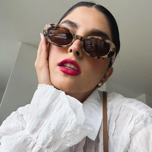 Modelo utilizando óculos de sol feminino Rosa Coral Ravena, armação Tartaruga e lente Marrom – estilo sofisticado e proteção UVA e UVB 400 para os olhos.