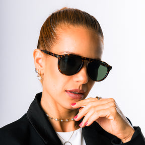 Modelo utilizando óculos de sol feminino Rosa Coral Sassari, armação Leopardo e lente Verde – estilo sofisticado e proteção UVA e UVB 400 para os olhos.