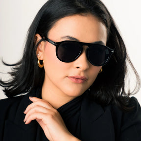 Modelo utilizando óculos de sol feminino Rosa Coral Sassari, armação Preta e lente preta – estilo sofisticado e proteção UVA e UVB 400 para os olhos.