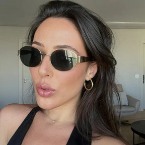 Modelo utilizando óculos de sol feminino Rosa Coral Selene, armação Dourada e lente Verde – estilo sofisticado e proteção UVA e UVB 400 para os olhos. 
