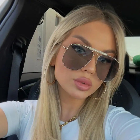 Modelo utilizando óculos de sol feminino Rosa Coral Sicilia, armação Dourada e lente Cinza – estilo sofisticado e proteção UVA e UVB 400 para os olhos.