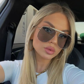 Modelo utilizando óculos de sol feminino Rosa Coral Sicilia, armação Dourada e lente Cinza – estilo sofisticado e proteção UVA e UVB 400 para os olhos.
