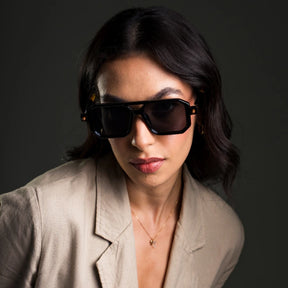Modelo utilizando óculos de sol feminino aviador Rosa Coral Villanova, armação Preta e lente Cinza – estilo sofisticado e proteção UVA e UVB 400 para os olhos.