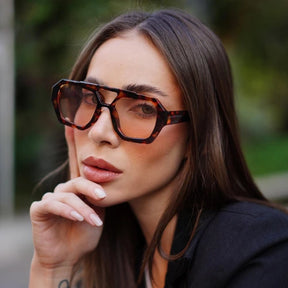 Modelo utilizando óculos de sol feminino Rosa Coral Zurich, armação Leopardo e lente Marrom – estilo sofisticado e proteção UVA e UVB 400 para os olhos.