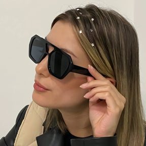 Modelo utilizando óculos de sol feminino Rosa Coral Zurich, armação Preta e lente Preta – estilo sofisticado e proteção UVA e UVB 400 para os olhos.
