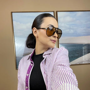 Modelo utilizando óculos de sol feminino Rosa Coral Marche, armação Preta e lente Marrom – estilo sofisticado e proteção UVA e UVB 400 para os olhos.