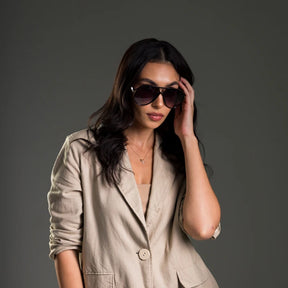 Modelo utilizando óculos de sol feminino Rosa Coral Marche, armação Preta e lente Roxo Degradê – estilo sofisticado e proteção UVA e UVB 400 para os olhos.